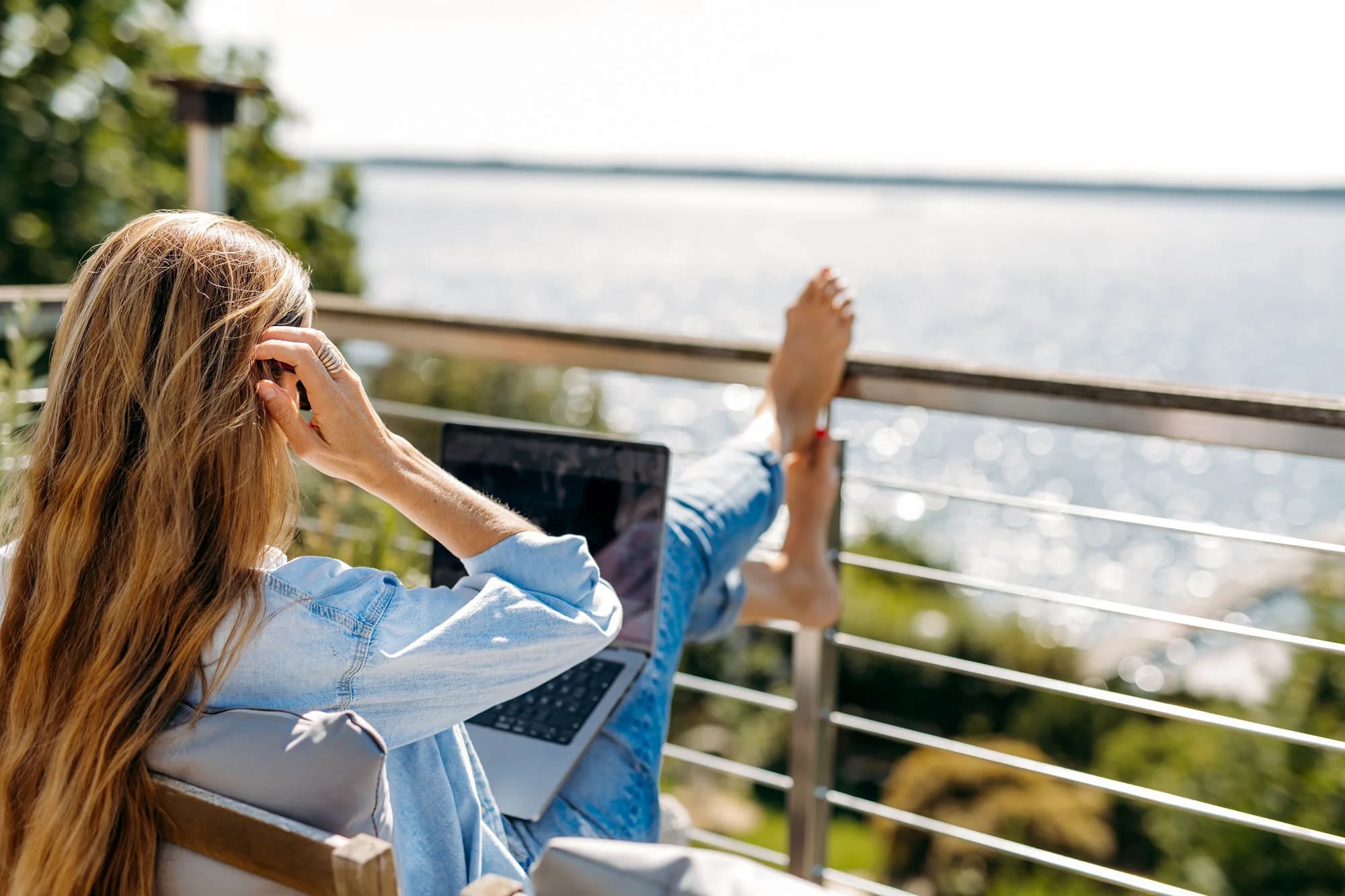 Sandra Seelig arbeitet mit einem Laptop und blickt in die Natur.
